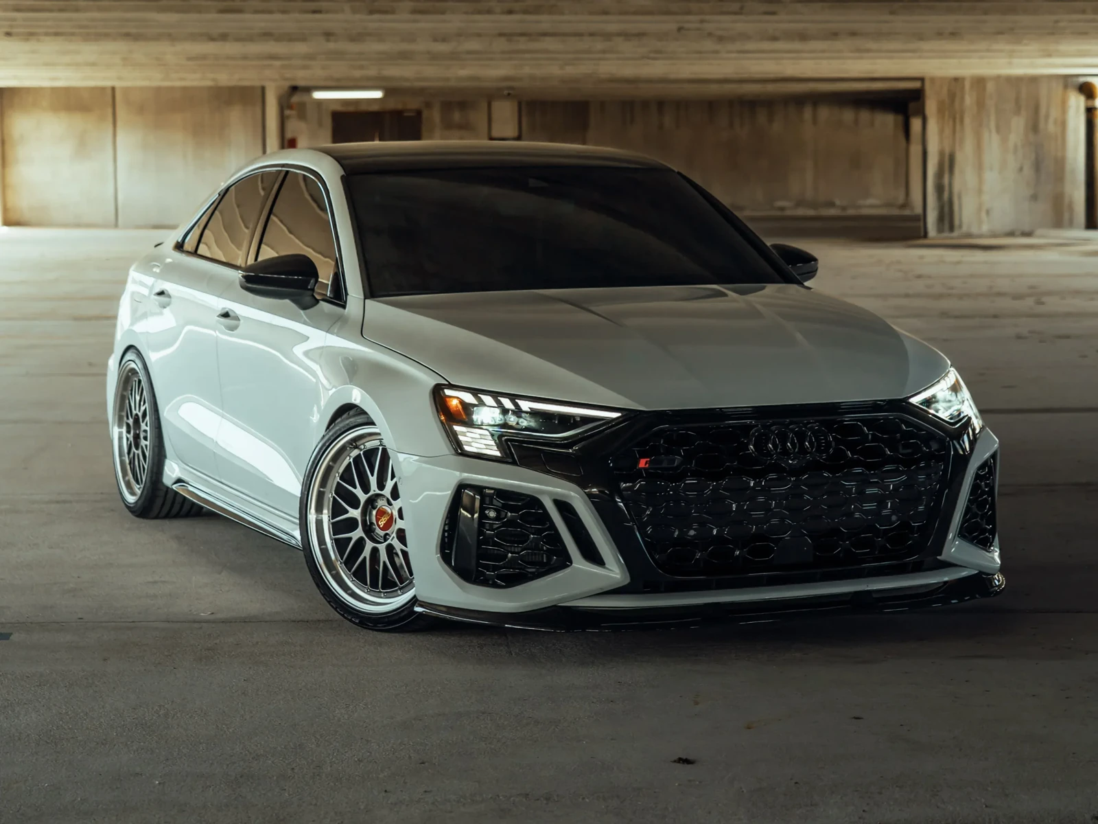 White Audi sedan with dark side windows in a parking garage.