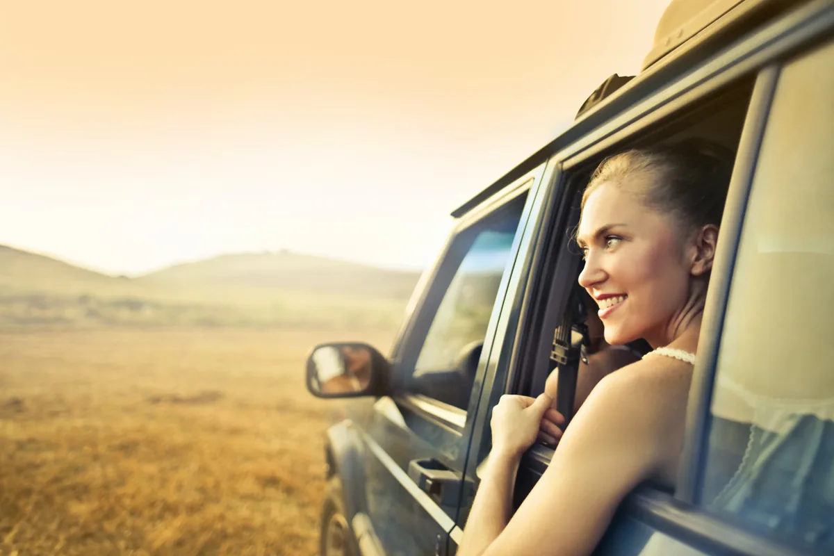 Passenger looking through a car window in bright sunlight.