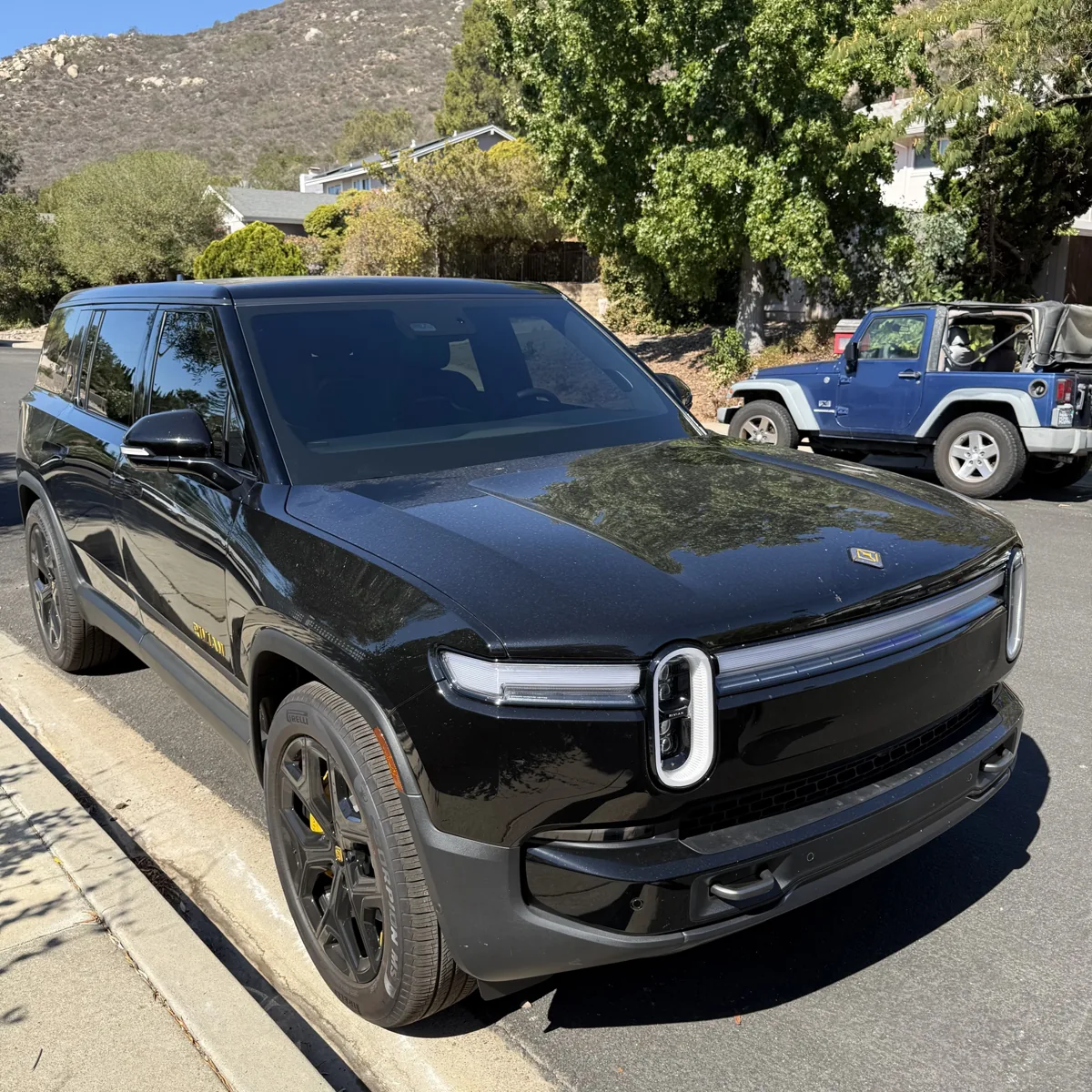 Front three-quarter view of a black Rivian R1S with Nano Ceramic IR windshield and front door tint in Poway