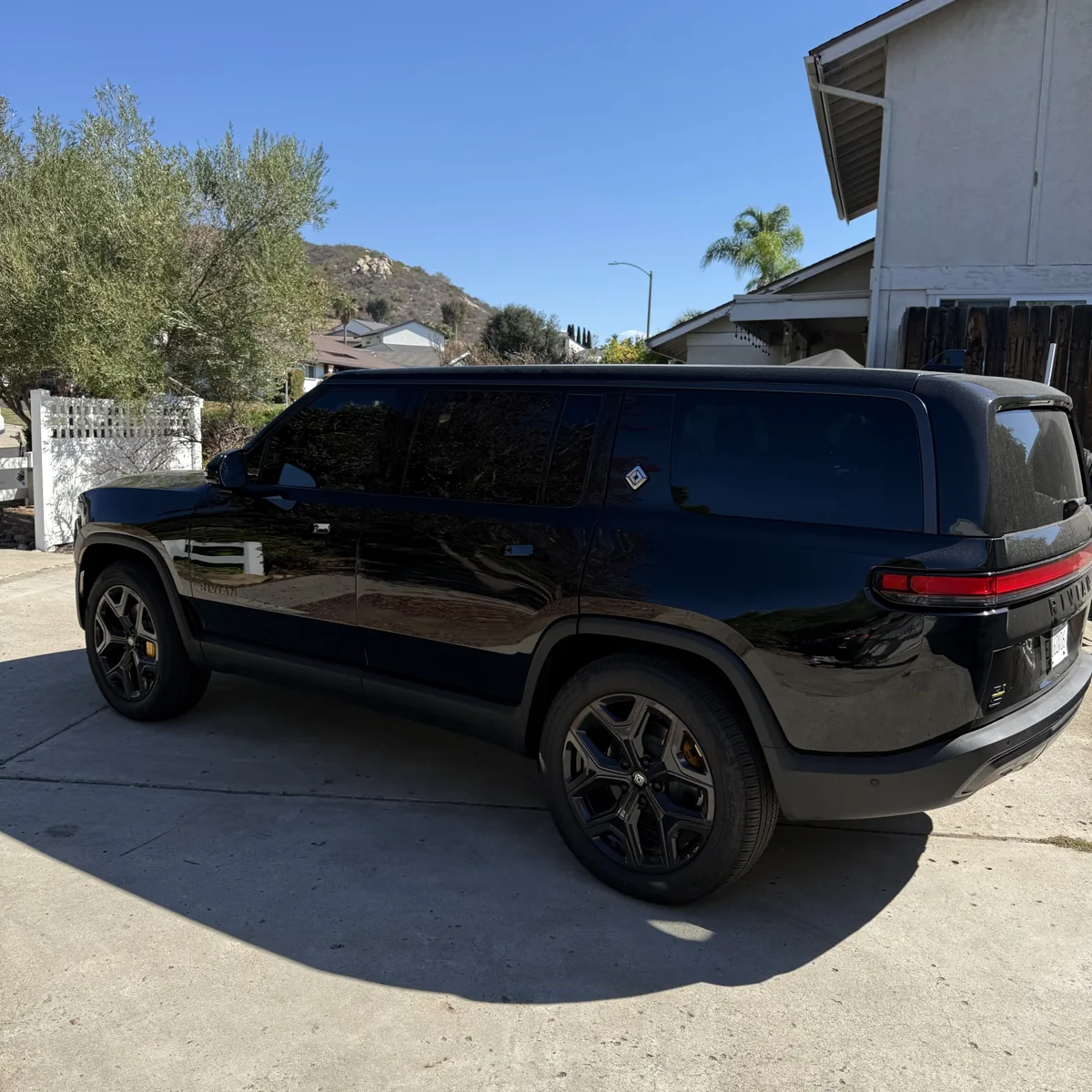 Rear three-quarter view of the black Rivian R1S in Poway with its existing factory privacy glass